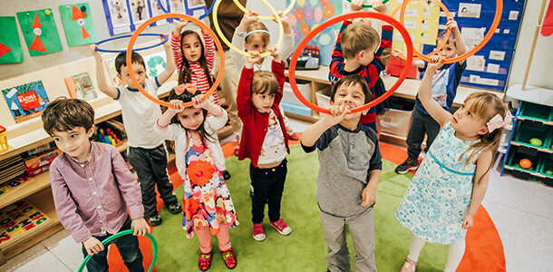 a group of kids holds hula hoops above their heads in a French preschool in New York