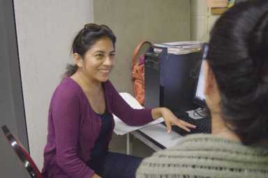 A smiling woman seated at a piano, playing keys indoor.