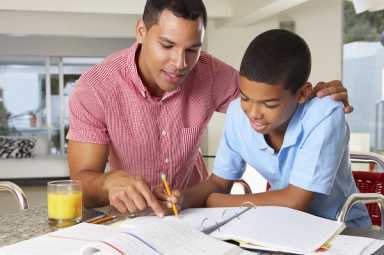 Father Helping Son With Homework In Kitchen