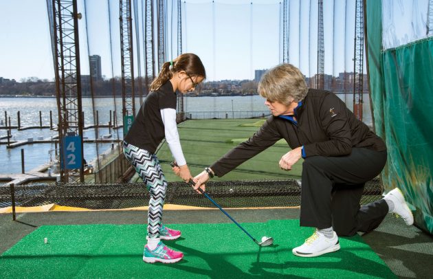 instructor showing girl how to hit golf ball