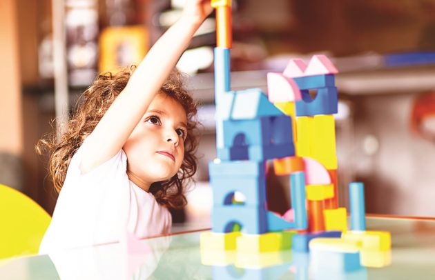 Little girl building a house with cubes, indoors.