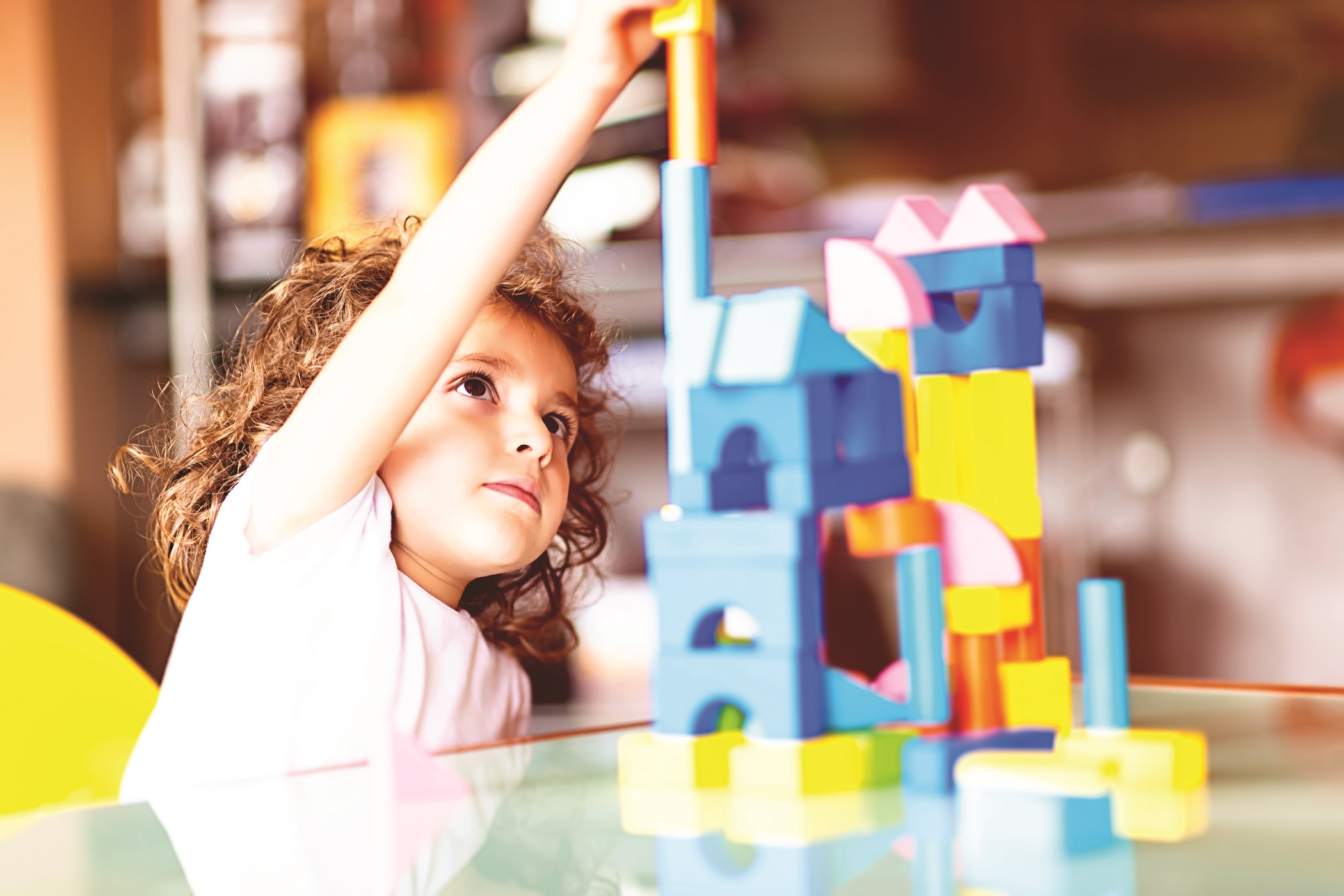 Little girl building a house with cubes, indoors.