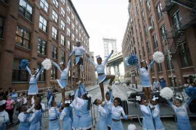 cheerleaders in cobblestone street in front of bridge