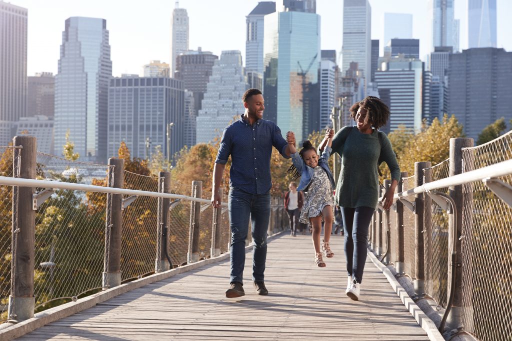 Young african-american parents with daughter taking a walk on footbridge on the highline in new york city