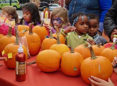 kids with face paint decorating pumpkins