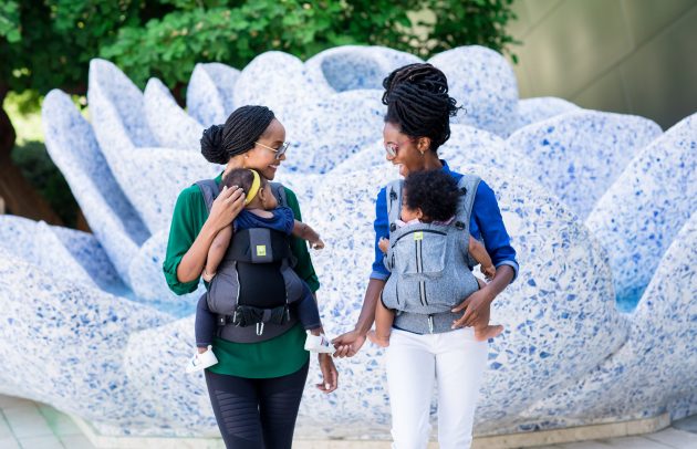 two moms holding babies in carriers
