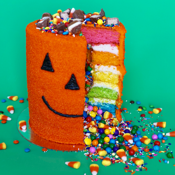 pumpkin explosion cake with one slice cut out and candy spilling out