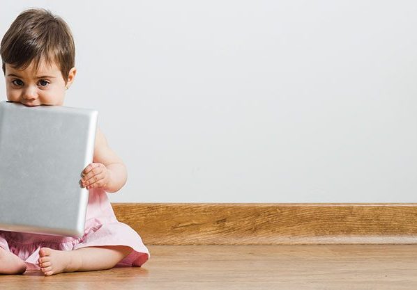 toddler holding ipad sitting on wood floor
