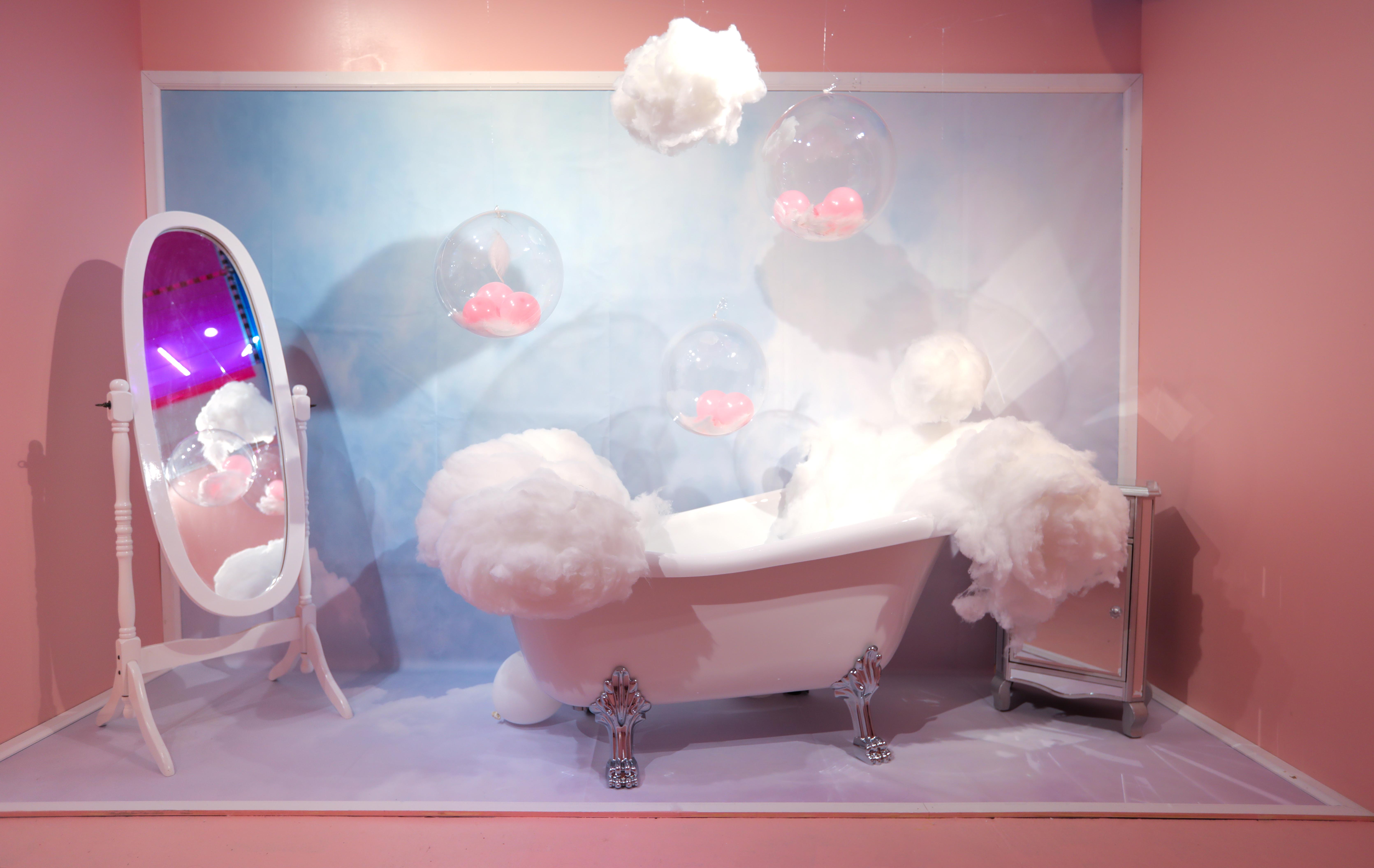 whimsical bath tub overflowing with fluffy foam in front a full length mirror