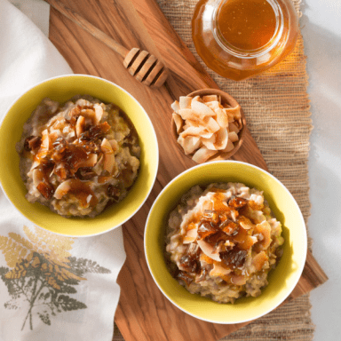 flatlay shot of two bowls of oatmeal wit a pot of honey