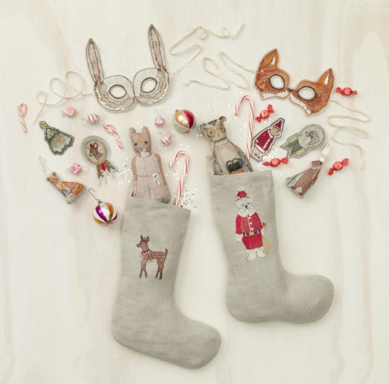 linen christmas stockings with cute animal embroidery laid out in a flatlay with toys spilling out
