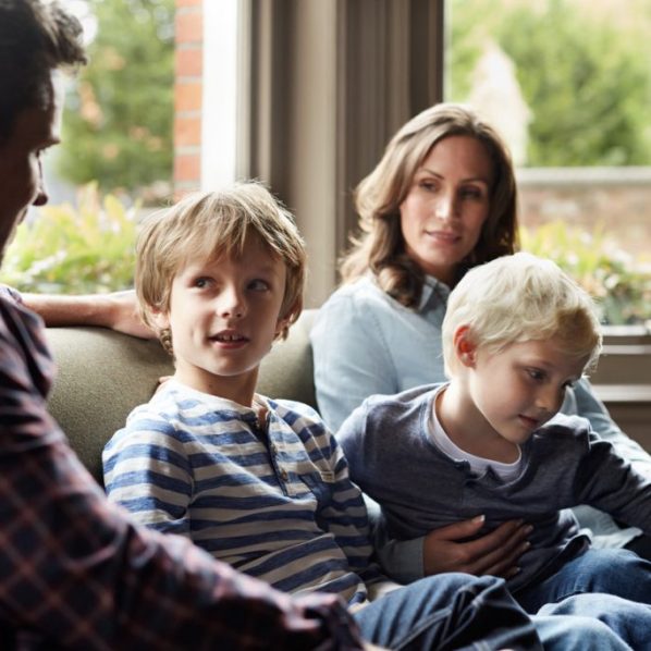 family of four gathered together talking on a couch