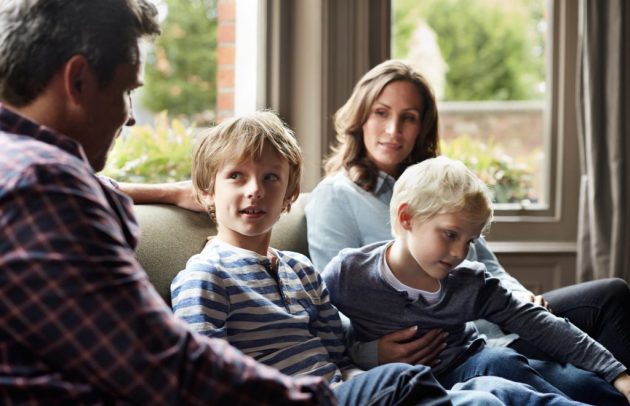 family of four gathered together talking on a couch