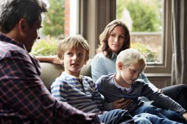family of four gathered together talking on a couch