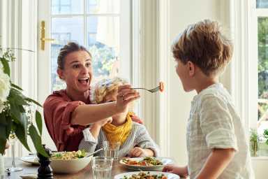 mom feeding her little kid at the table