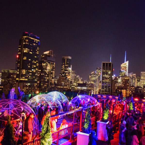rooftop igloos lit up in color with a view of new york city