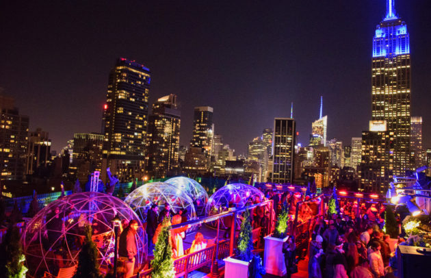 rooftop igloos lit up in color with a view of new york city