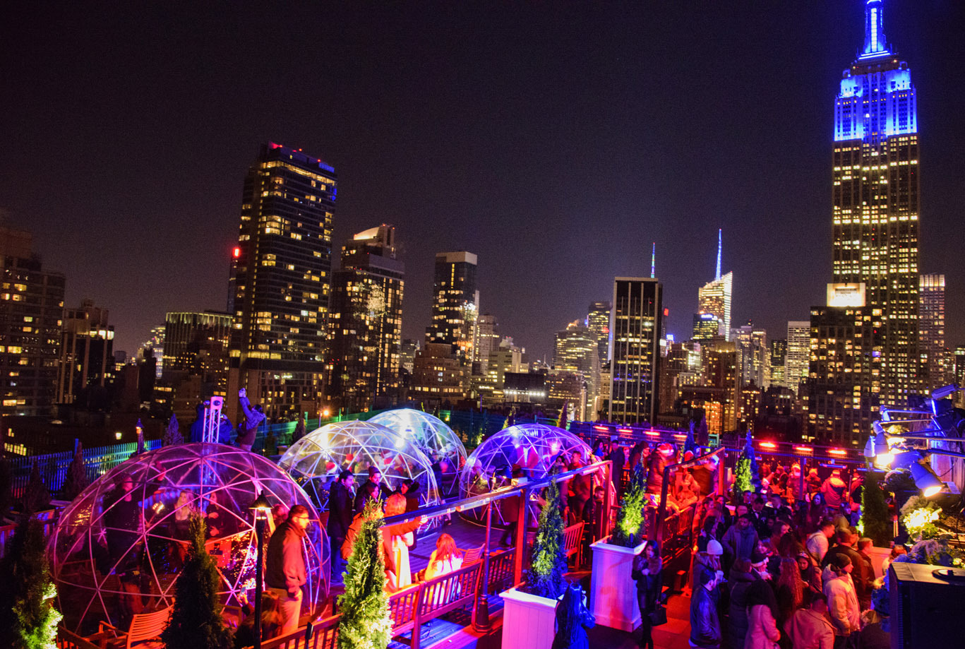 rooftop igloos lit up in color with a view of new york city