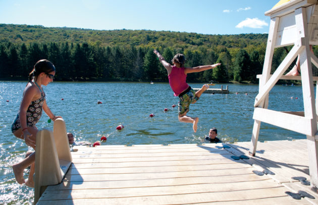 camper jumping into a lake from a dock at summer camp