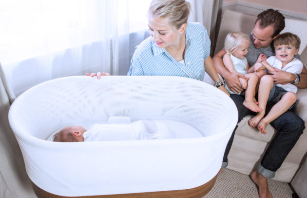 mom looking at baby sleeping and family in the background