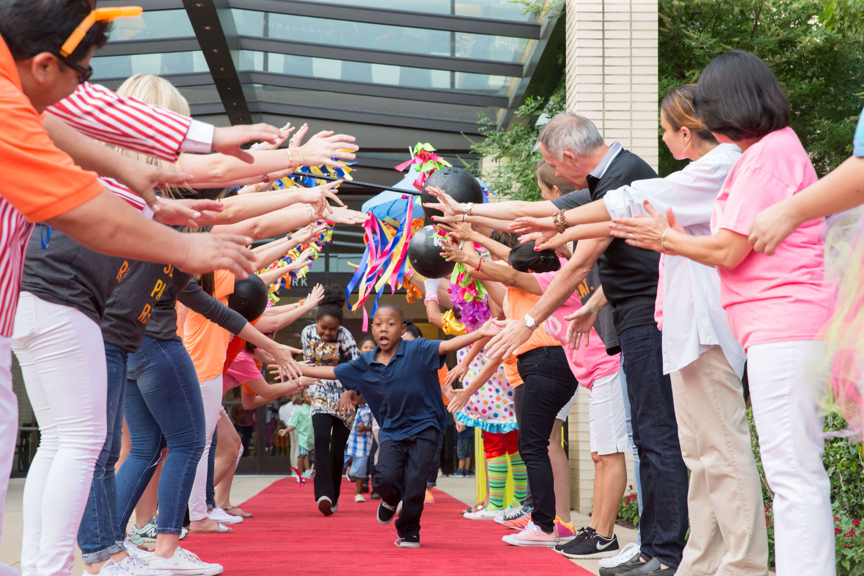 kids running down a red carpet giving high fives