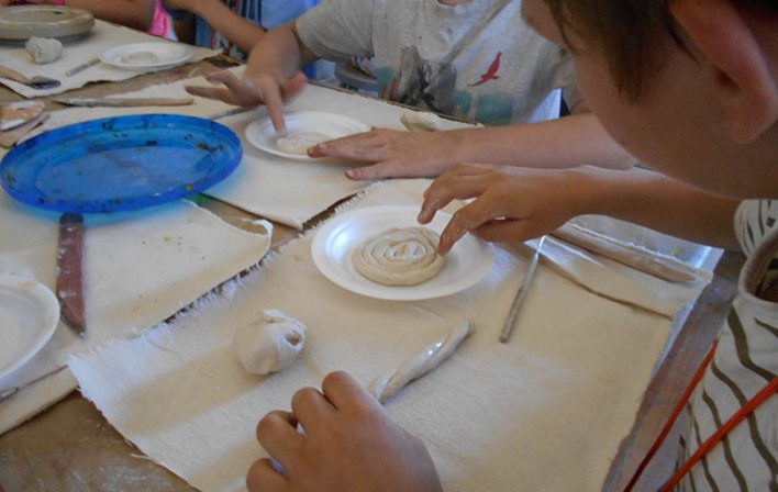 child touches coil of clay