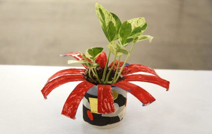 a plant sits in an upcycled can-turned-flowerpot on a white table