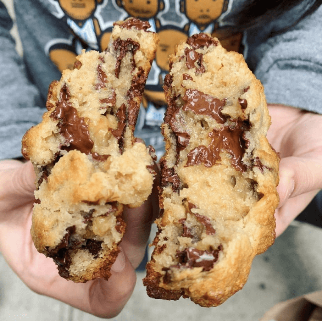 overhead view of a person splitting a chocolate chip cookie 