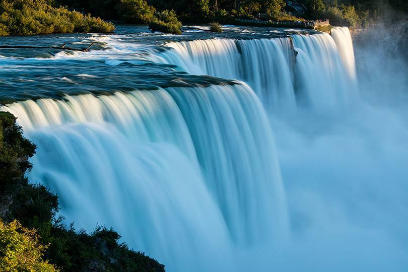 a surreal waterfall with sunlit green foliage around it