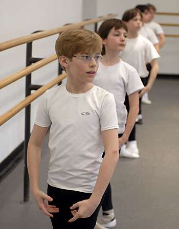 four boys plié next to a wooden barre in a dance class