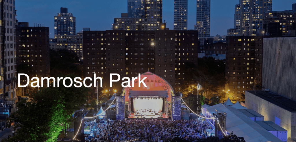 a bandshell in Damrosch Park is lit up as artists play to a full crowd