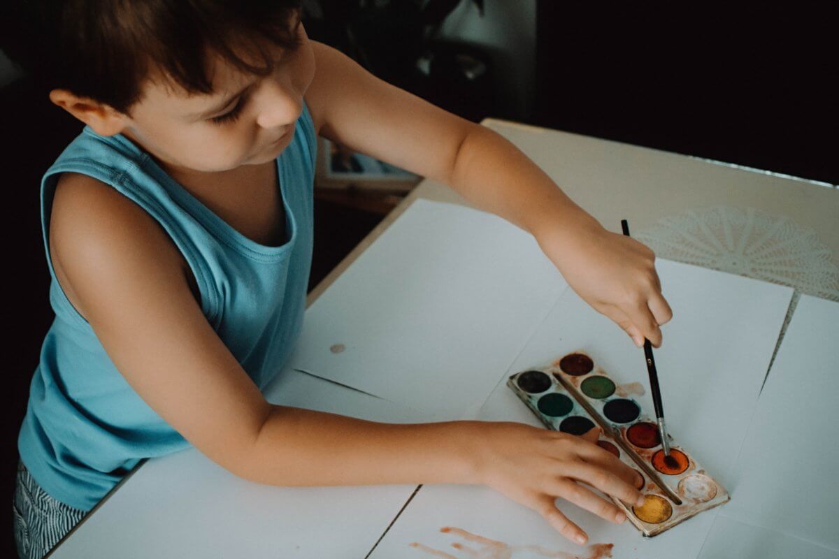 young boy painting with water colors