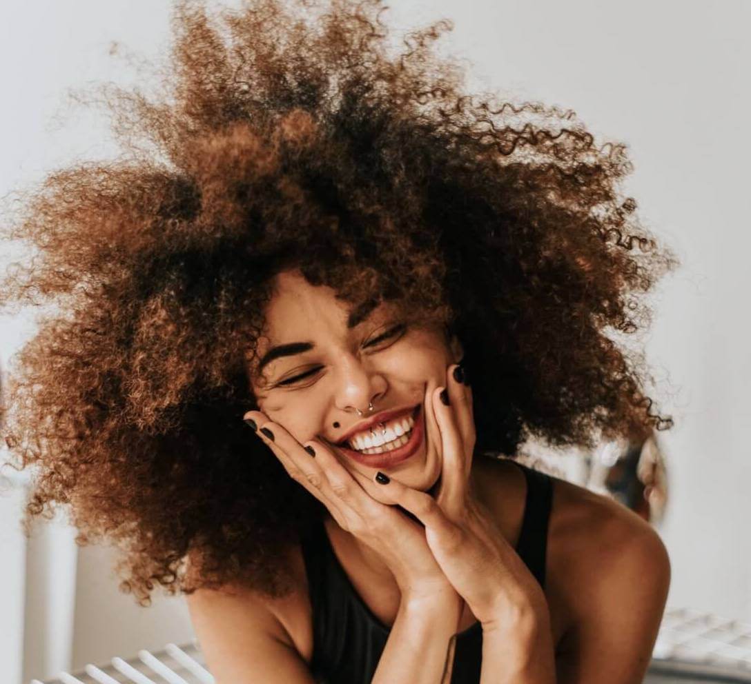 woman smiling and touching her face