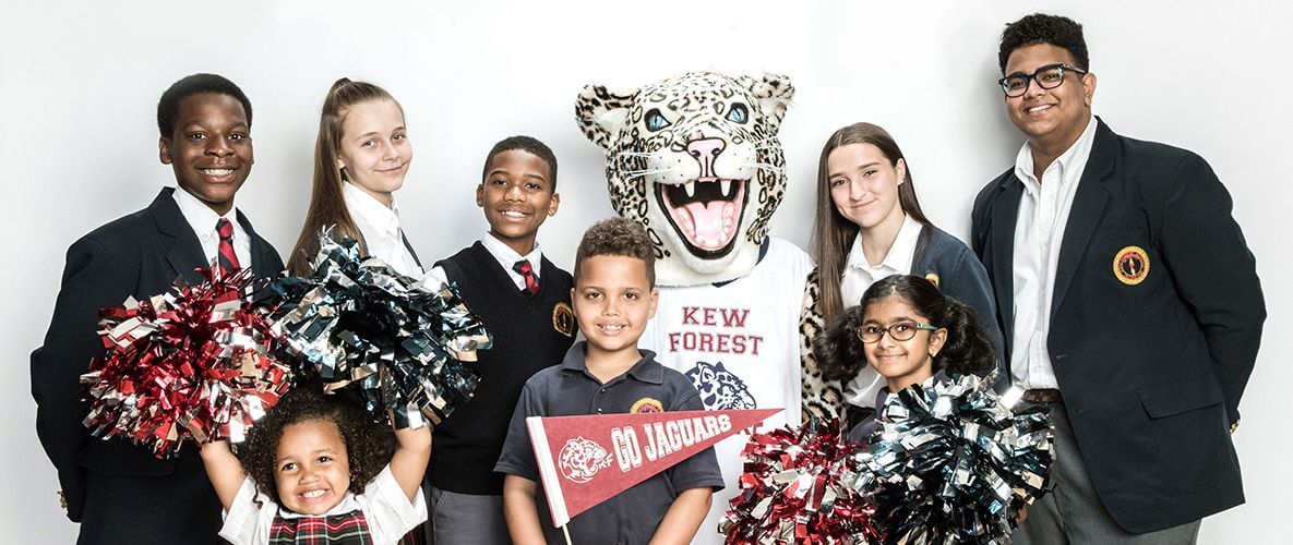 A school mascot in a jaguar costume poses with children holding pom-poms and a "Go Jaguars" pennant; faces are blurred.