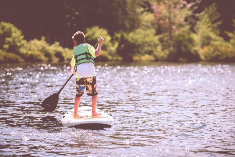 child paddling on the lake first time at summer camp