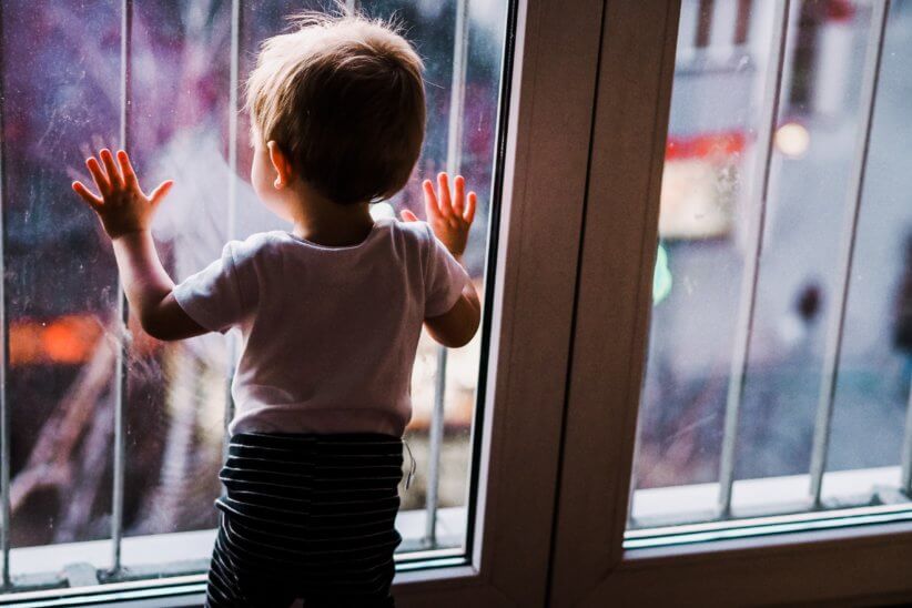 young boy looking outside window