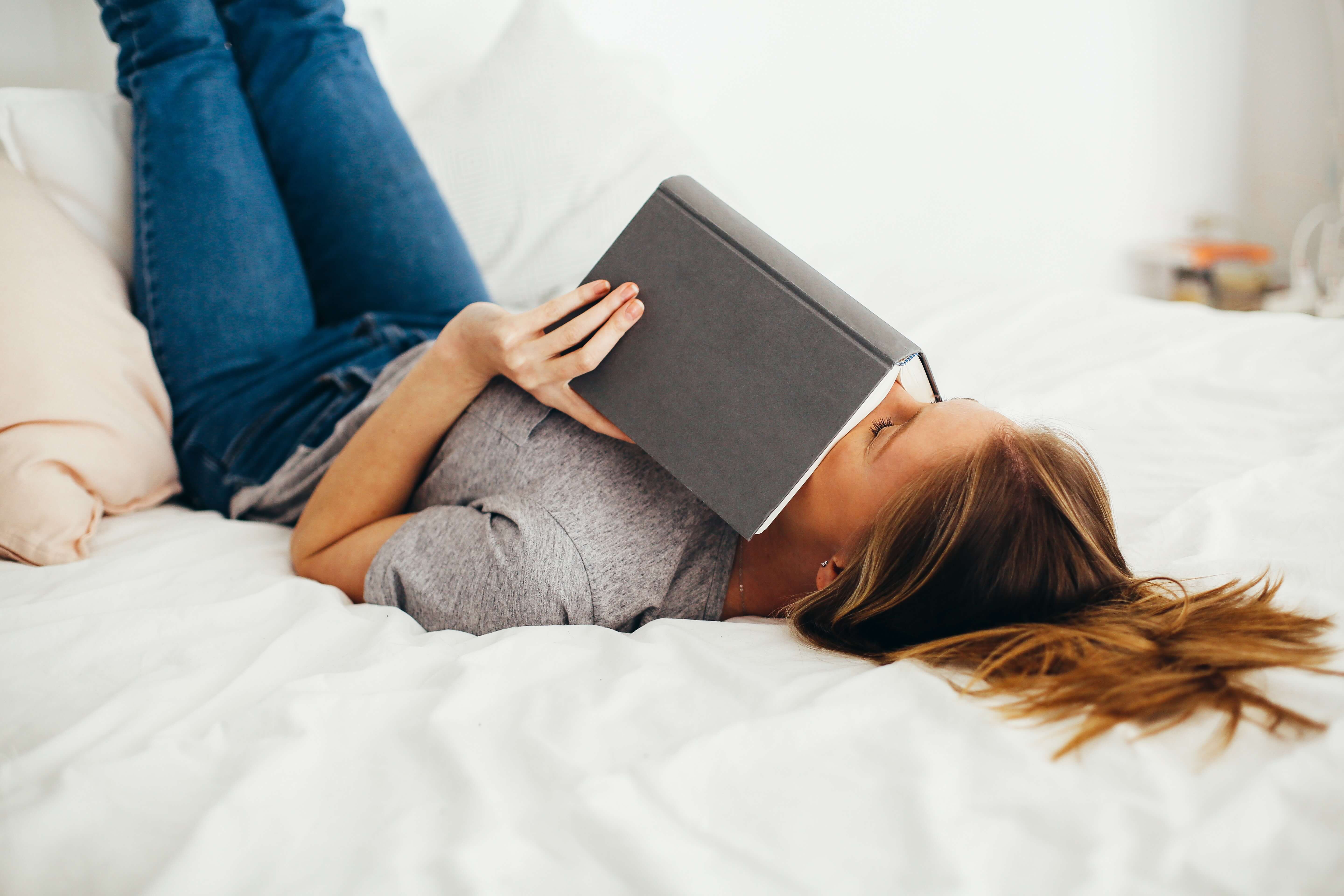 woman laying on the bed reading a book