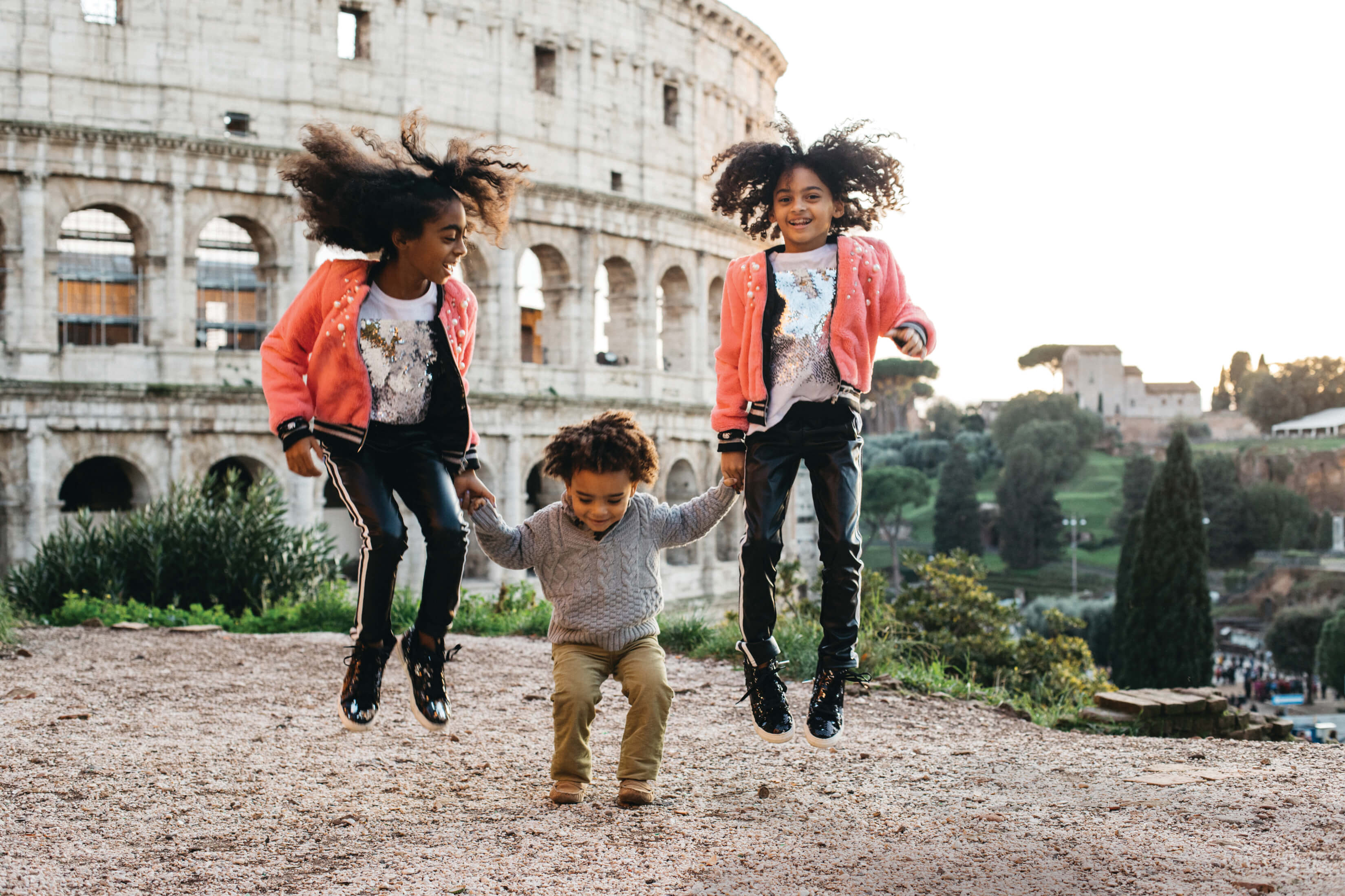 kids jumping in front of the colosseum in Rome