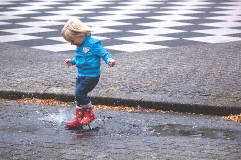 kid jumping in puddle with rain boots