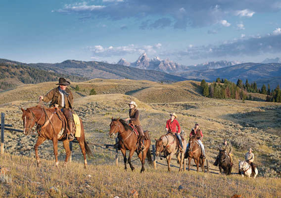 Dude Ranchers riding on horseback in the plains