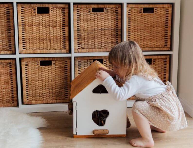 girl-playing-with-a-wooden-toy-house-3933028-800×1200