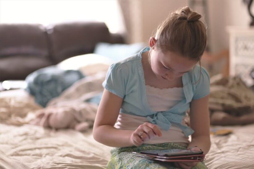 girl sitting on bed playing educational apps