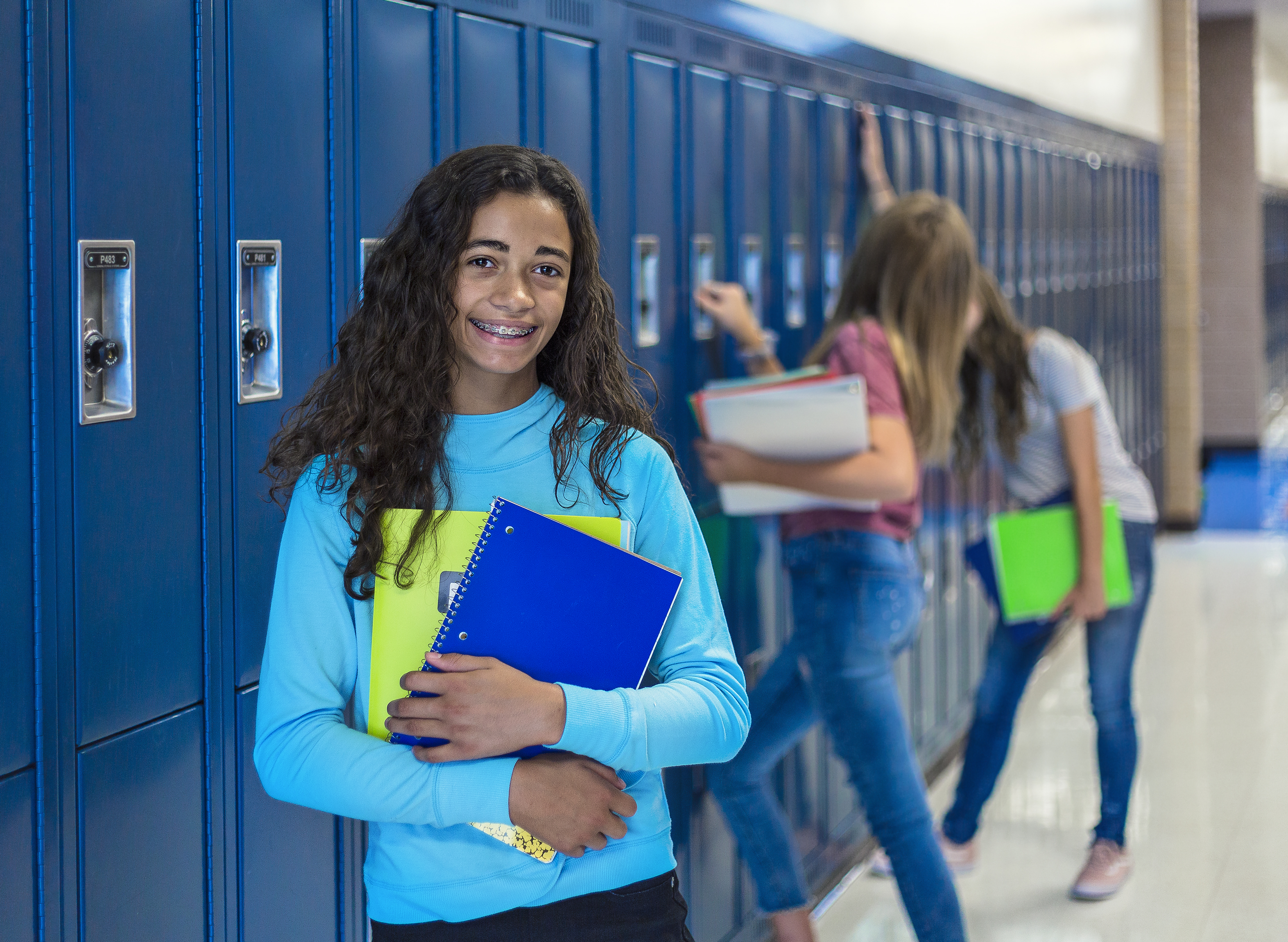 African American female junior high school student portrait, smiling in a school hallway