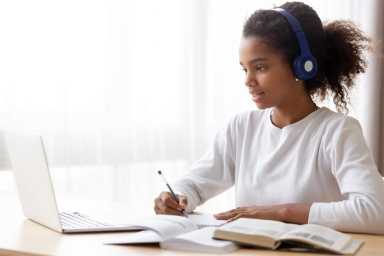 African American teen girl wearing headphones learning language online