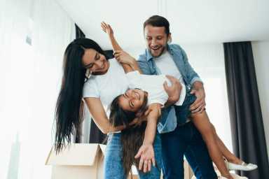 Happy parents playing with child at his new home. Funny spending time with family at home