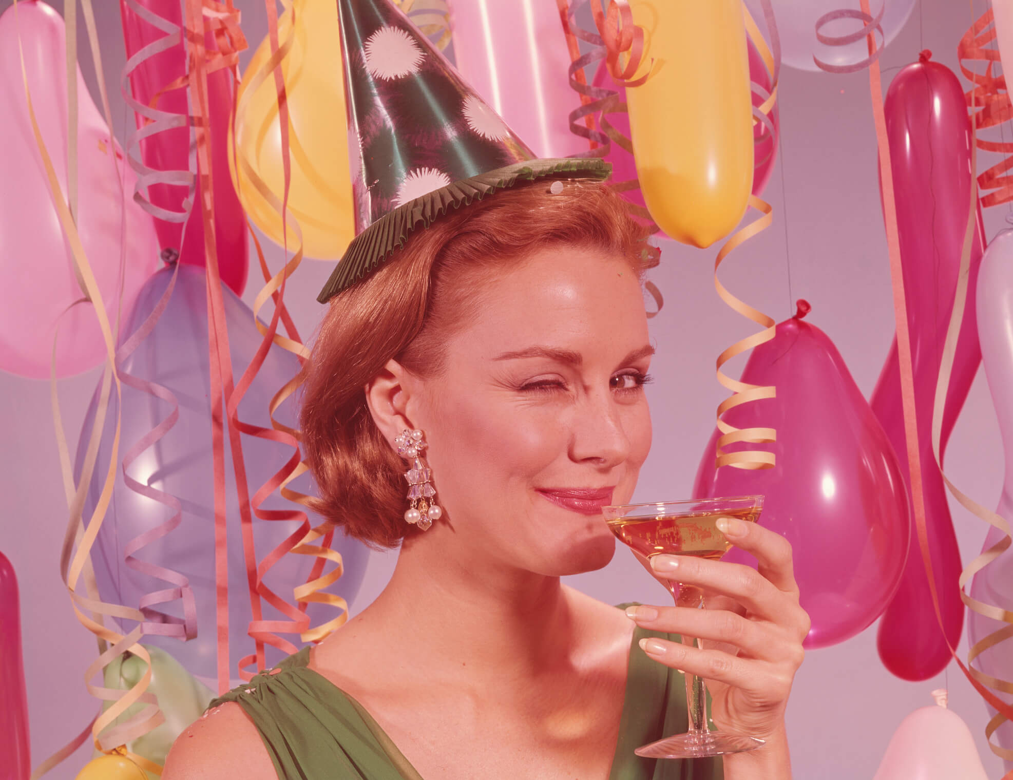 Woman at party, wearing party hat and winking, holding glass of wine. (Photo by H. Armstrong Roberts/Retrofile/Getty Images)