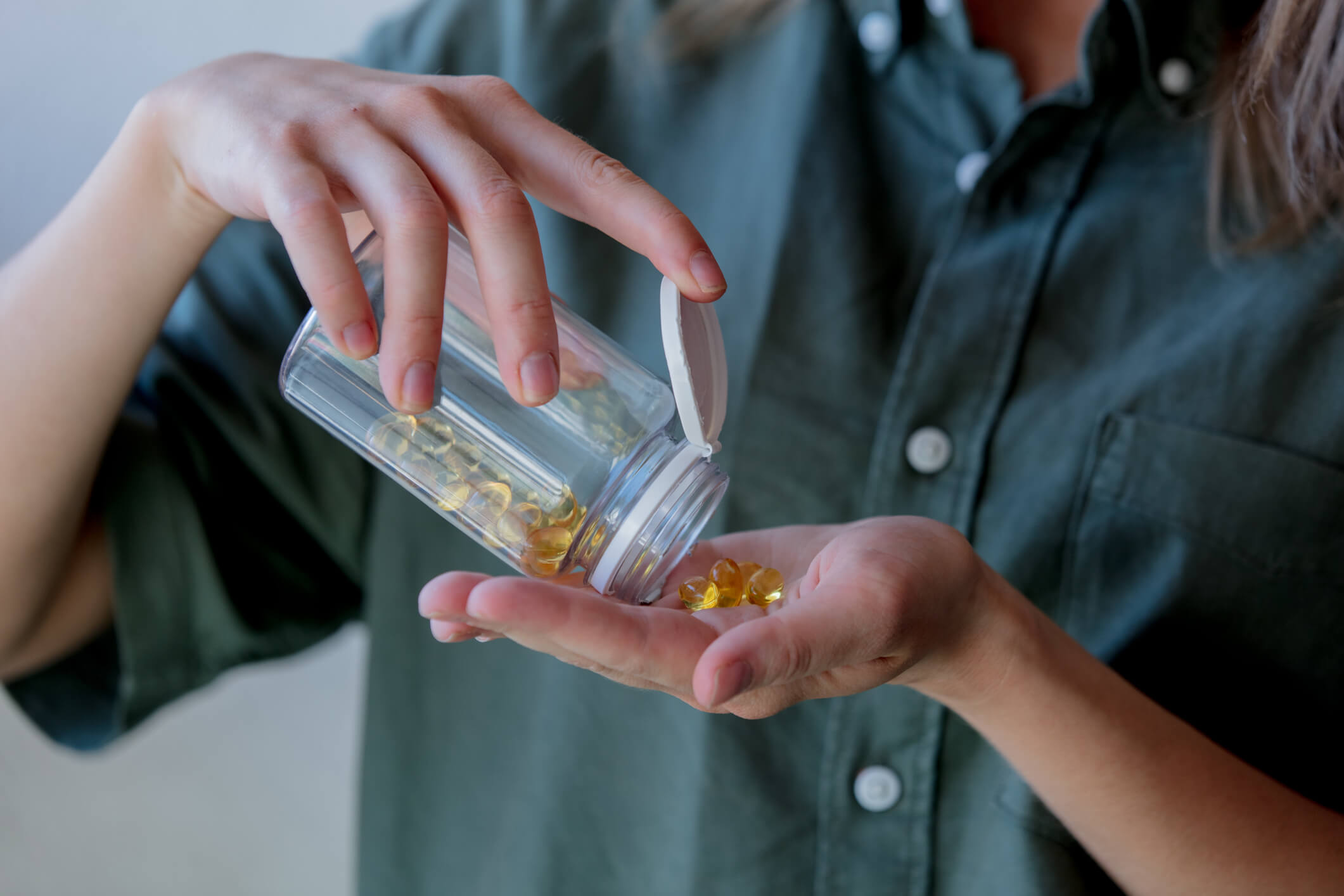 woman pours out of a jar pills with cod liver oil