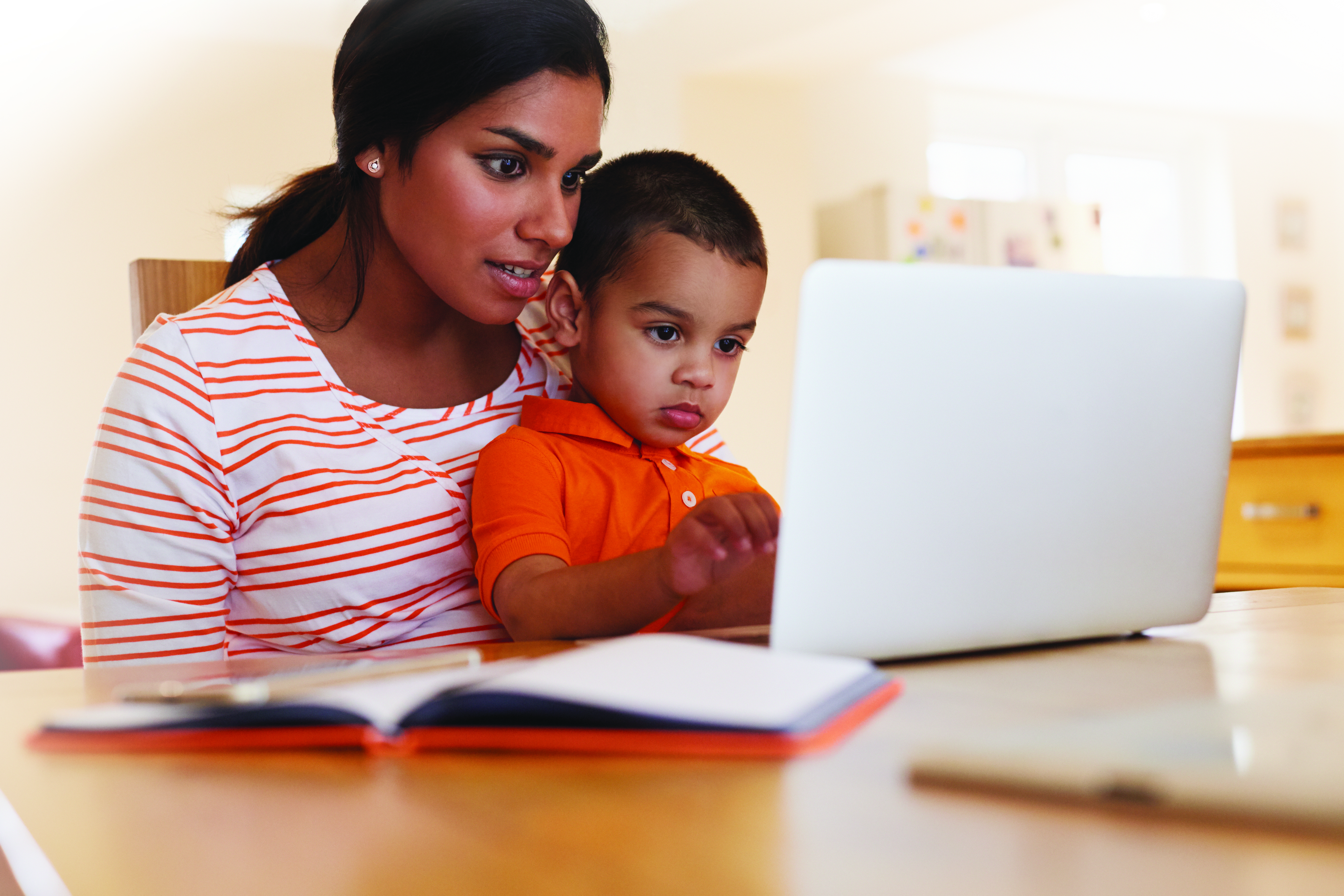 Mother And Son In Kitchen Looking At Laptop Together