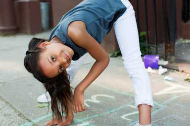 Girl playing on sidewalk, smiling