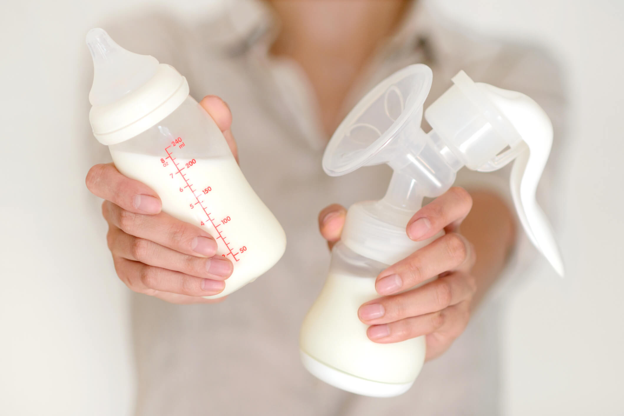 Breast pump and bottle with milk in woman’s hand